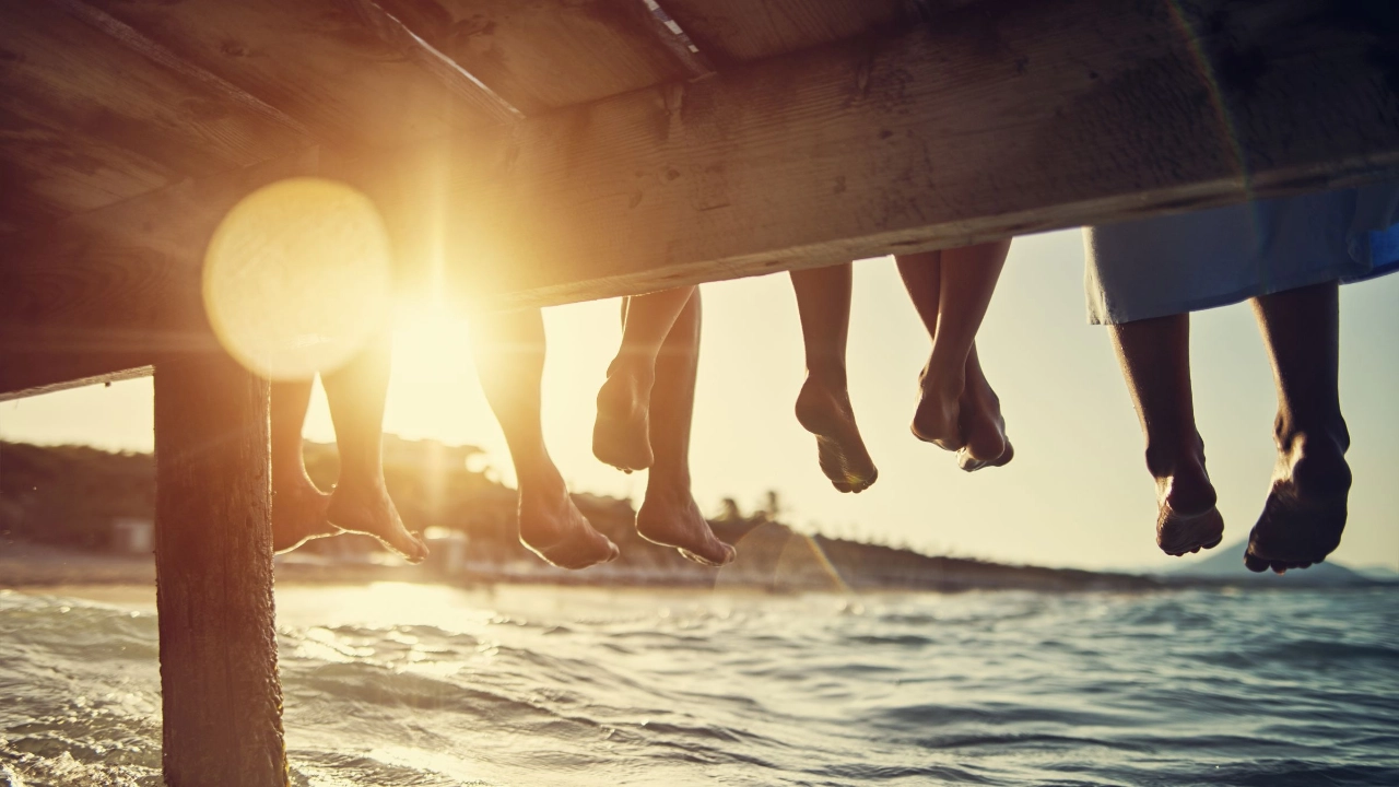 Familie sitzt bei Sonnenuntergang am Pier am Meer