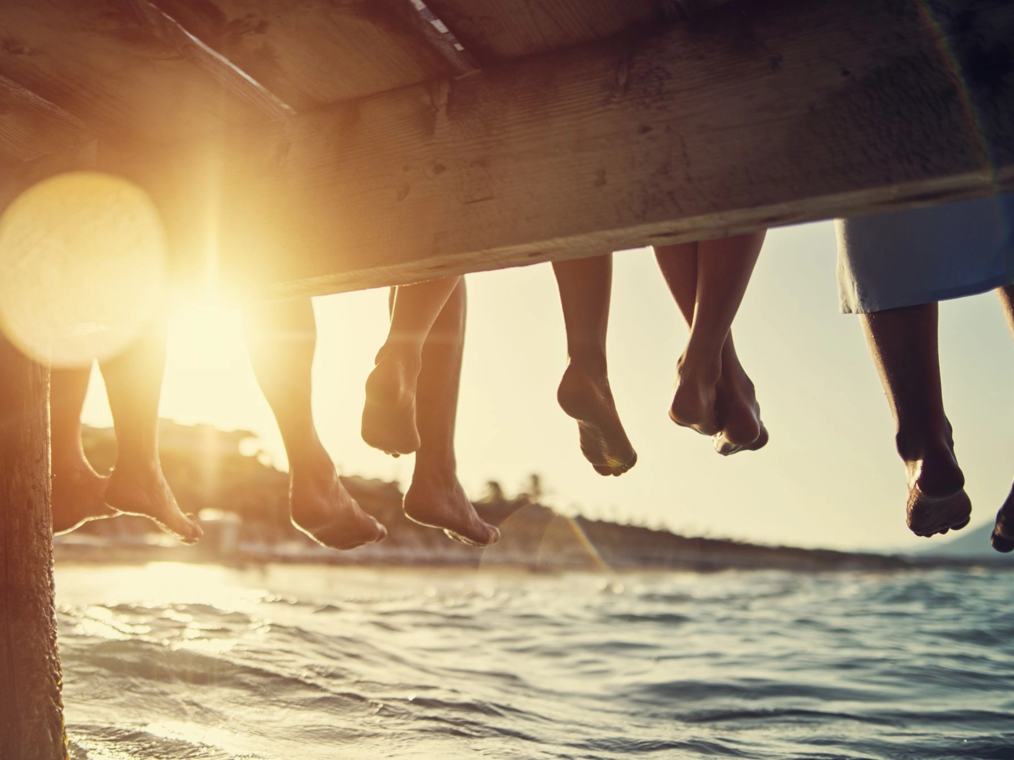 Familie sitzt bei Sonnenuntergang am Pier am Meer